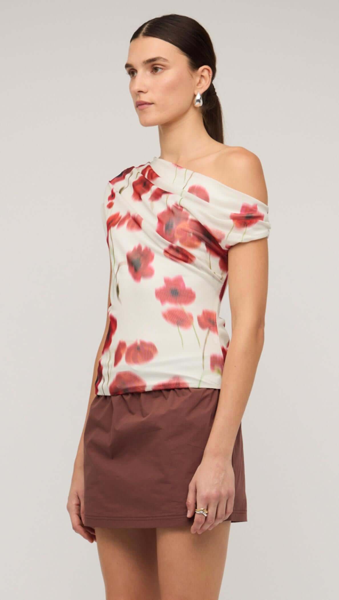 Model wearing a red and white poppy print off-shoulder mesh top paired with a brown skirt.