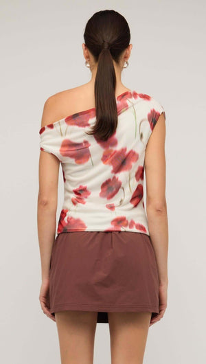Back view of a red and white poppy print off-shoulder mesh top, paired with a brown mini skirt.