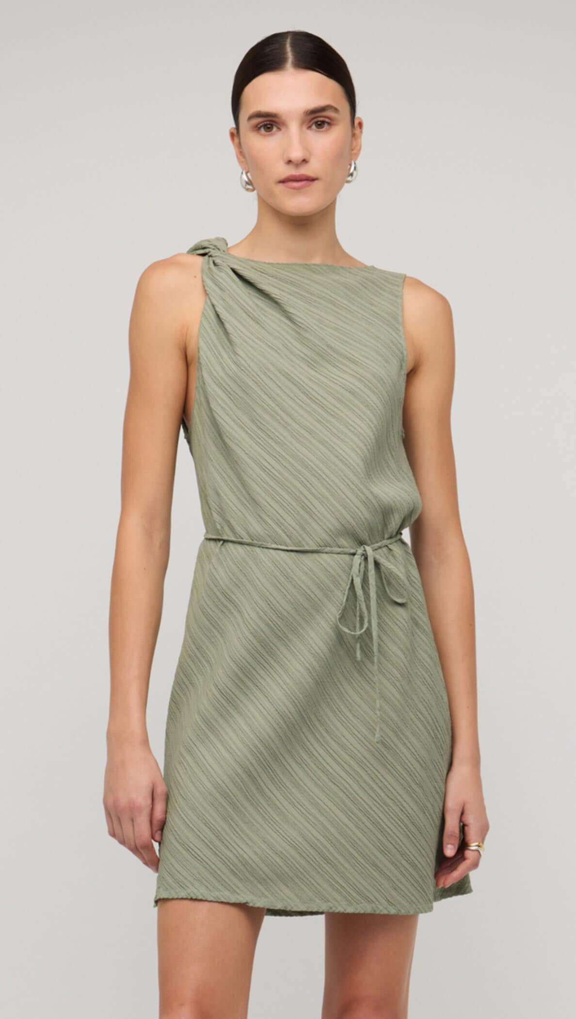 Sage green mini dress with tie waist, featuring a one-shoulder design and textured fabric.