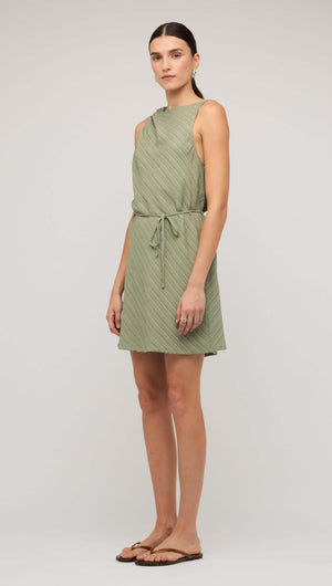 Model wearing a sage green mini dress with tie waist, featuring a sleeveless design and relaxed fit.