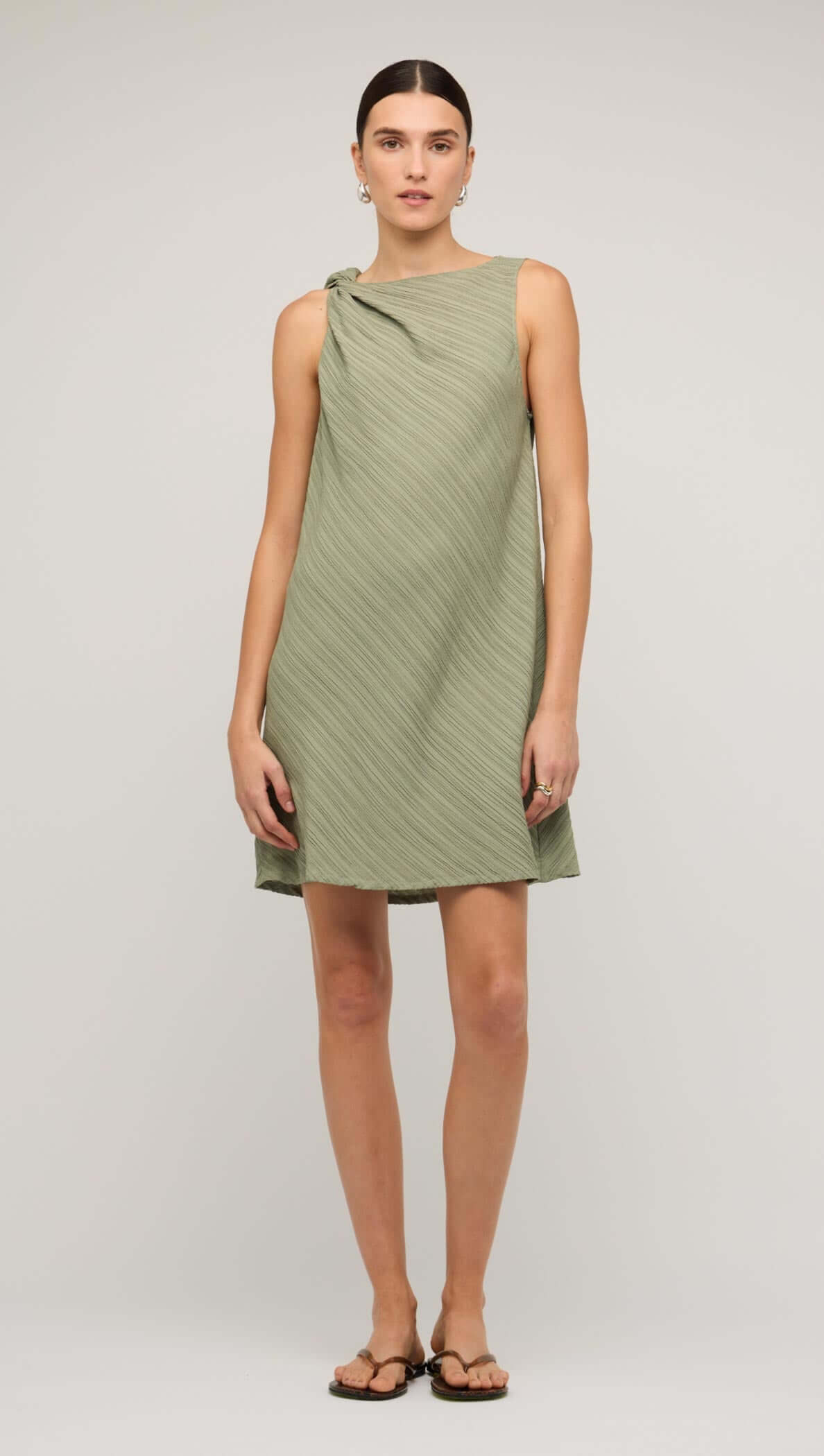 Sage green mini dress with tie waist, featuring a modern design and relaxed fit, perfect for casual outings.
