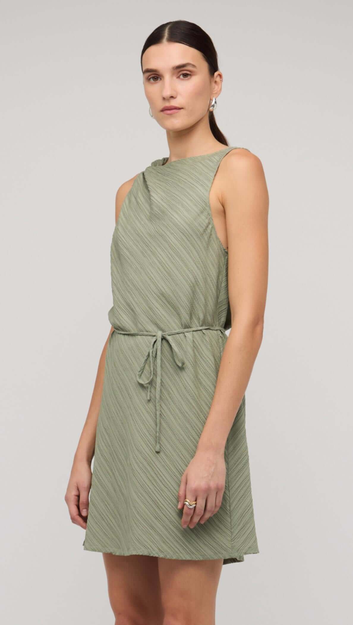 Sage green mini dress with tie waist, featuring a stylish sleeveless design and a flattering fit.