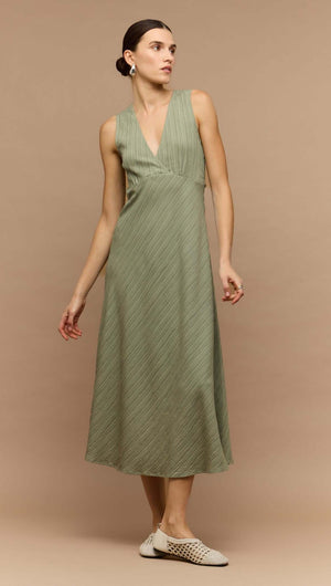 Model wearing a sage green v-neck bias midi dress, featuring a sleek design and elegant silhouette.