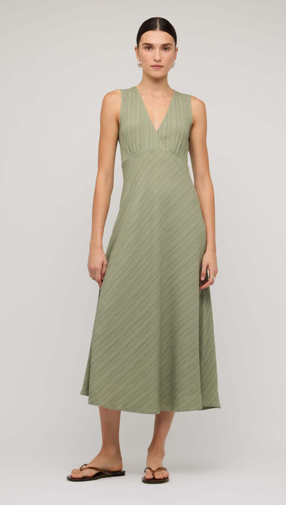 Sage green V-neck bias midi dress with a flattering fitted bodice and flowing skirt, perfect for elegant occasions.