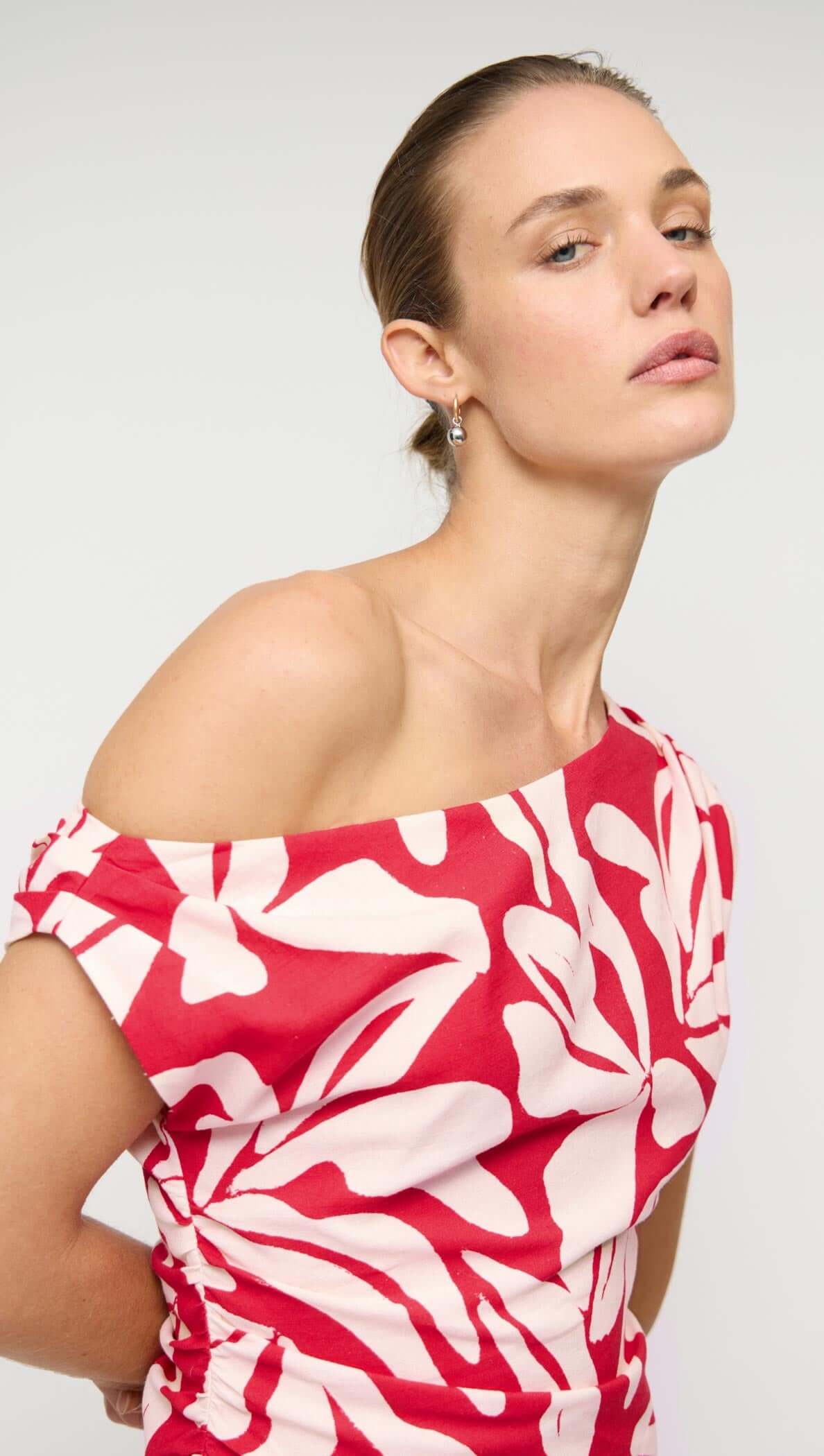 Cotton Blend Red & White Floral Asymmetrical Midi Dress modeled by a woman showcasing its elegant design and bold colors.
