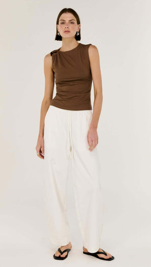 Brown Ruched Slinky Tank worn with white pants, showcasing soft ruching and unique shoulder detail.