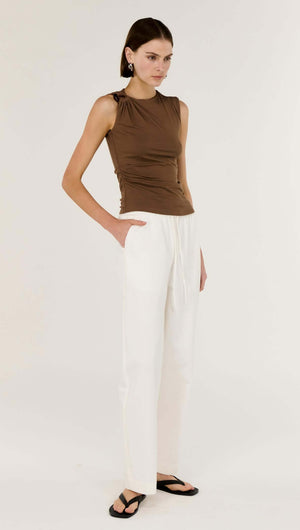 Model wearing a Brown Ruched Slinky Tank paired with white trousers, showcasing soft ruching and stylish shoulder detail.