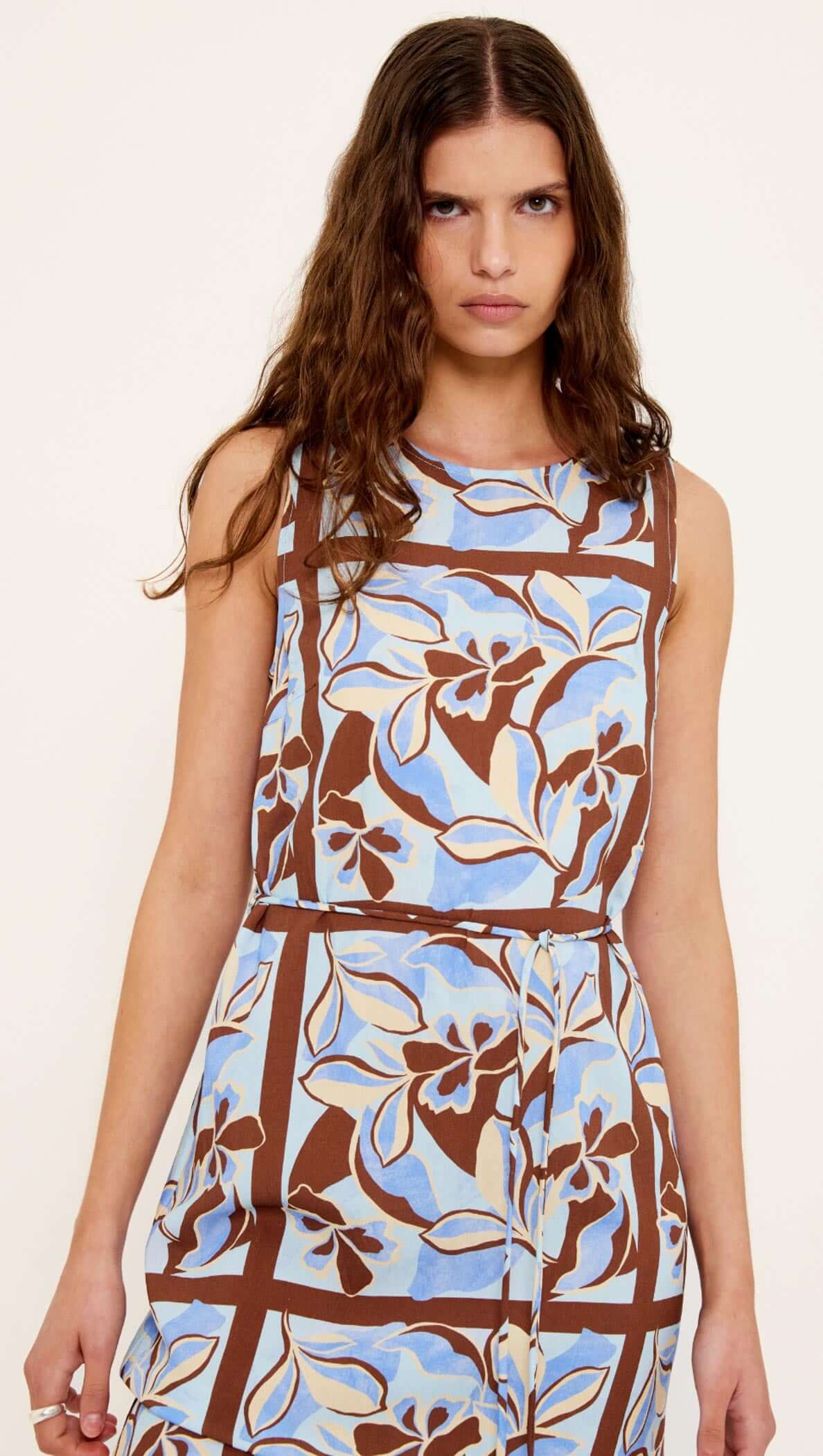 Blue Abstract floral Midi Dress with Tie Waist modeled on a woman, showcasing a sleeveless design and vibrant floral pattern.