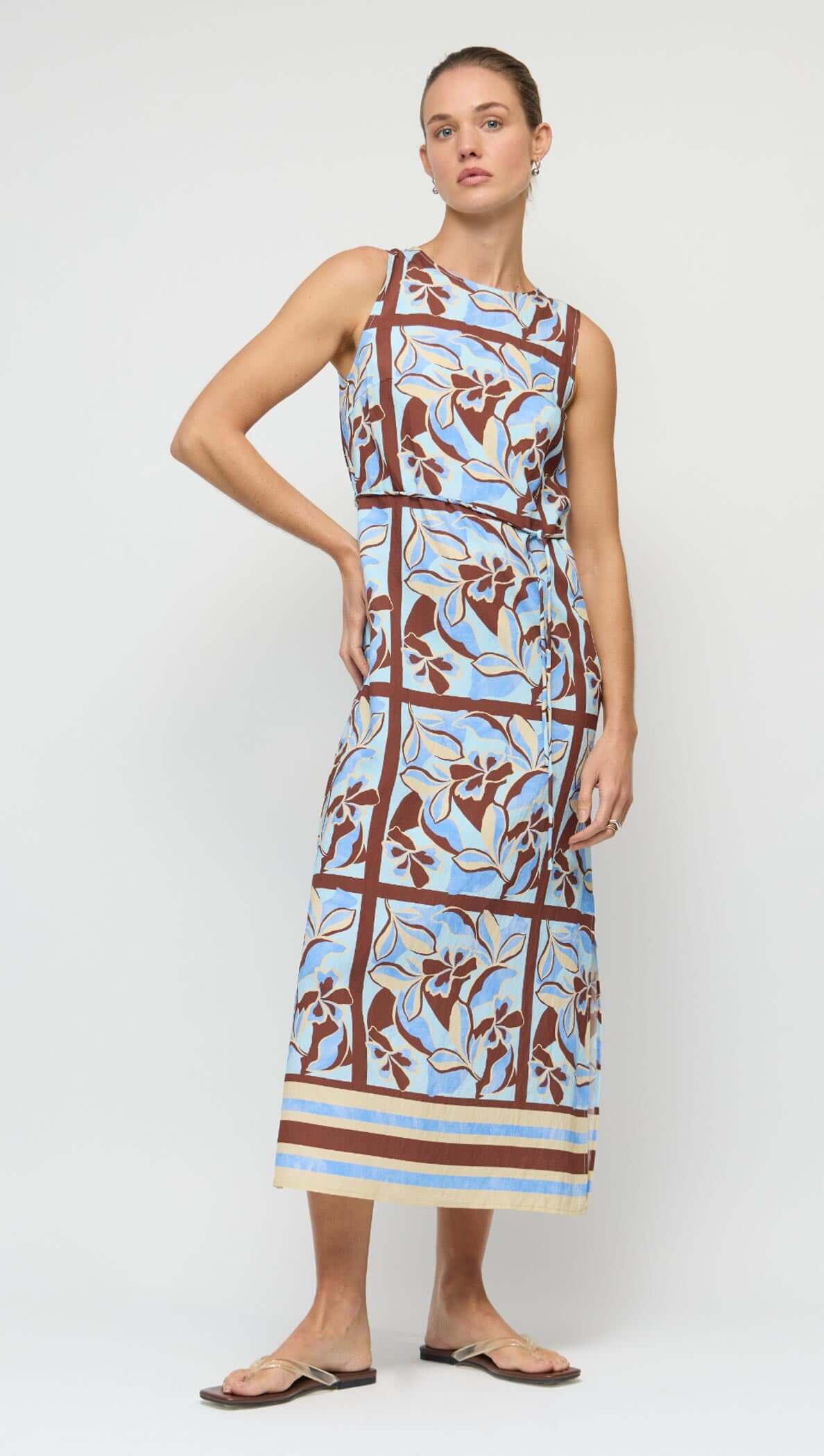 Blue Abstract floral Midi Dress with Tie Waist modeled on a woman, showcasing a sleeveless design and vibrant floral pattern.