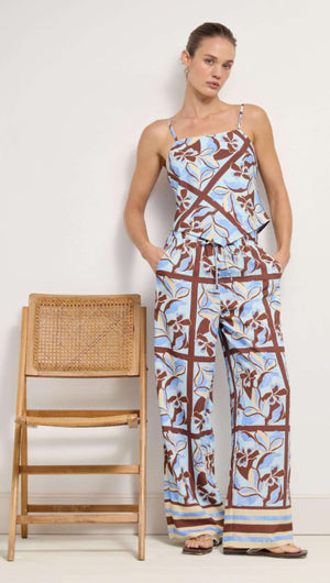 Blue Abstract floral Scarf Cami Top displayed on a model next to a wooden chair, showcasing its vibrant design.