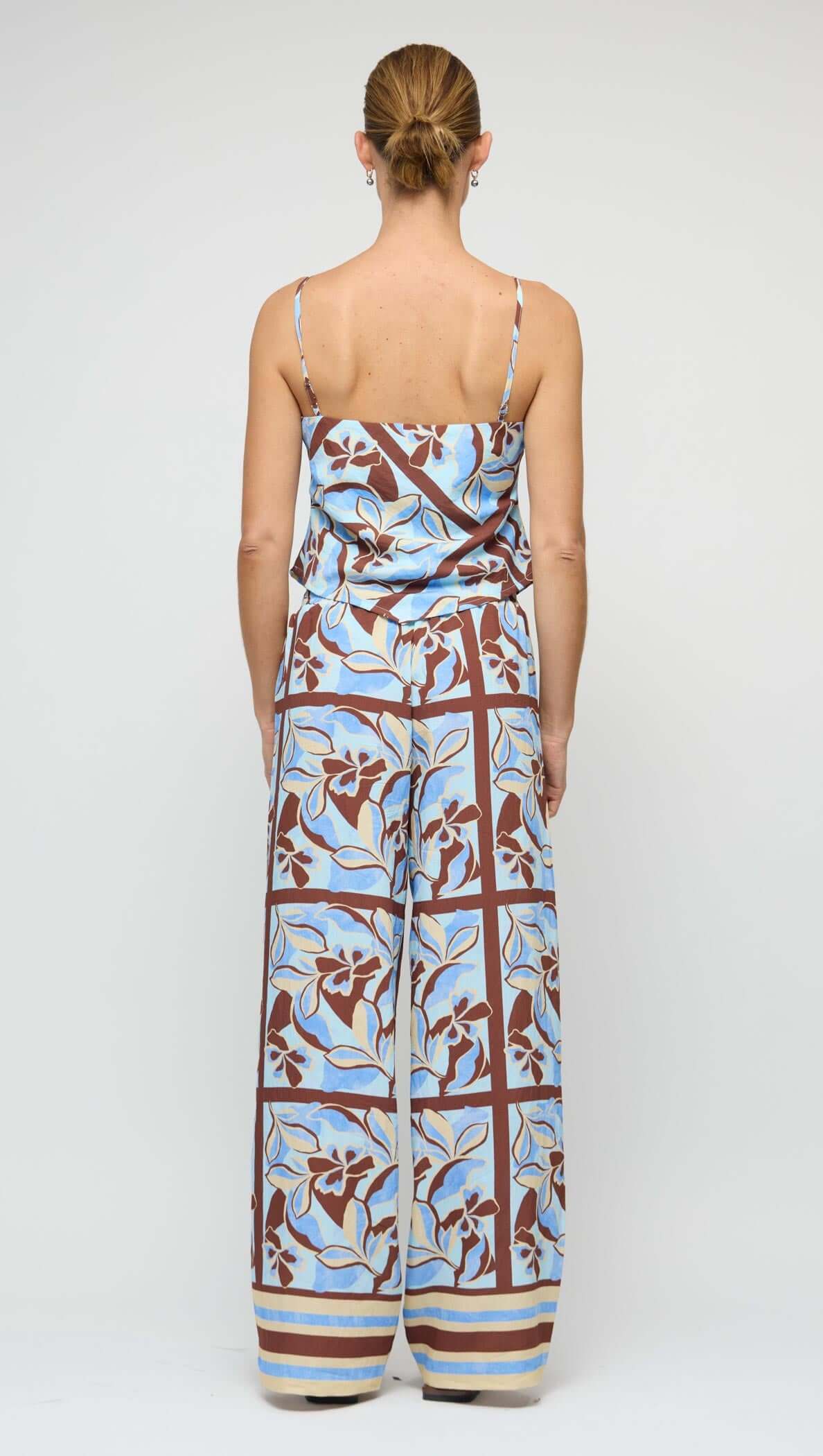 Back view of a woman wearing a Blue Abstract floral Scarf Cami Top with wide-leg pants, showcasing a summer outfit.