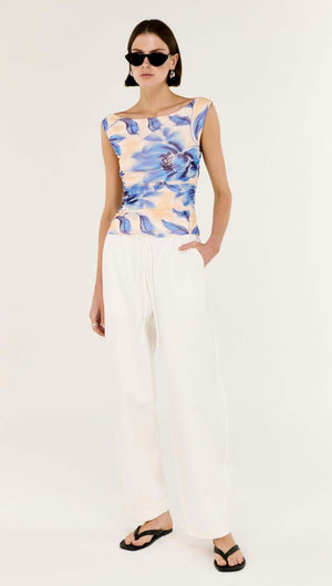 Model wearing a Blue Blurred Floral Mesh Top with white wide-leg pants and sunglasses.