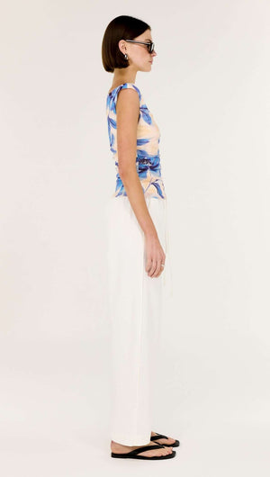 Model wearing the Blue Blurred Floral Mesh Top with white pants in a side view.