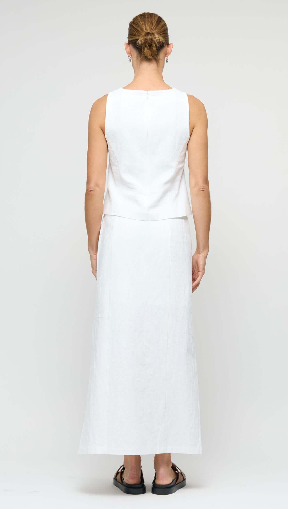 Back view of a model wearing a Linen Cotton Blend White Midi Skirt with a sleeveless top, showcasing the skirt's elegant silhouette.