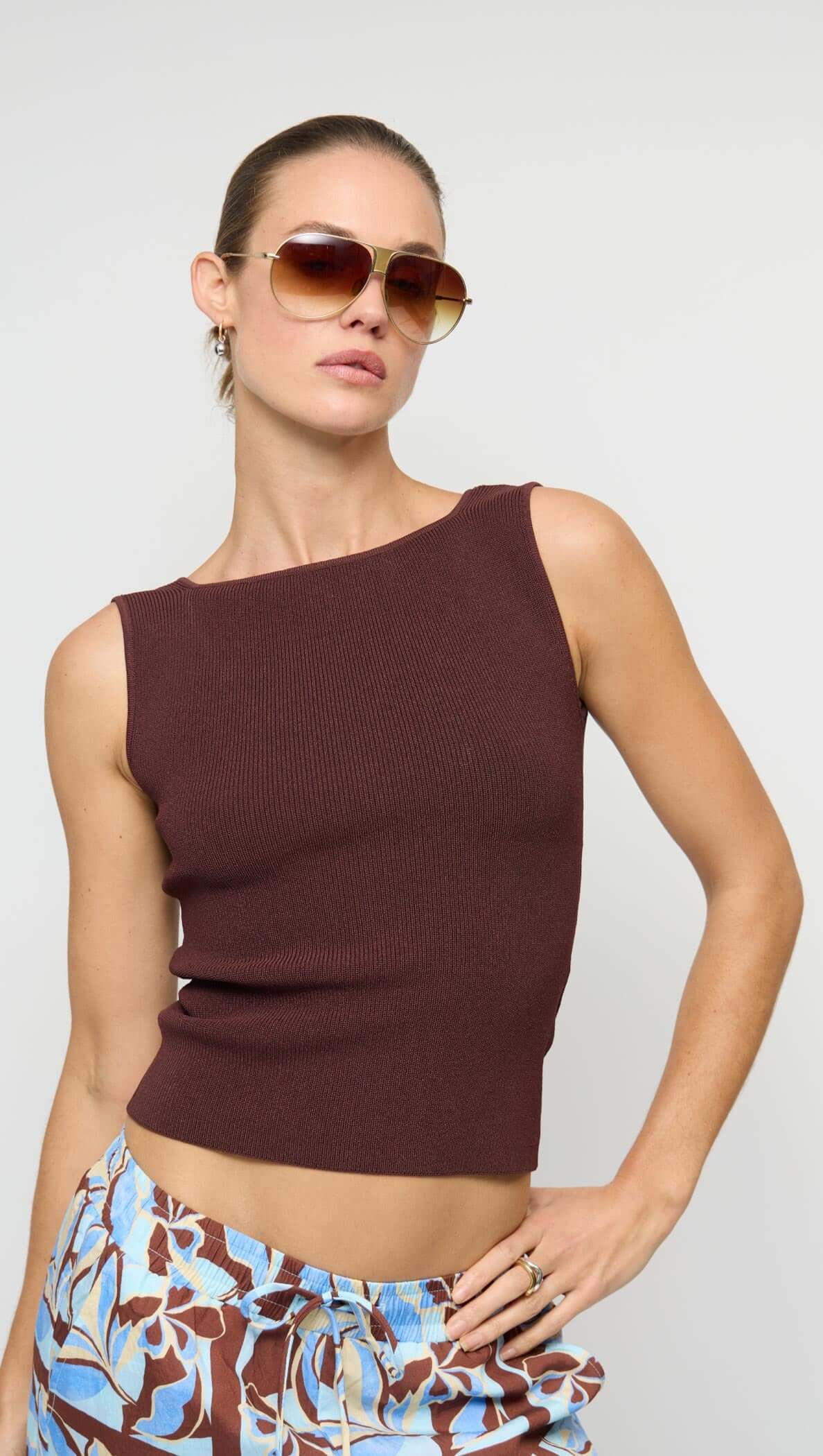 Model wearing Chocolate Brown Reversible Knit Tank Top with asymmetrical neckline and sunglasses, styled for a trendy look.