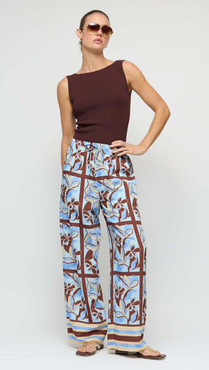 Model wearing Chocolate Brown Reversible Knit Tank Top with floral patterned wide-leg pants and sunglasses.