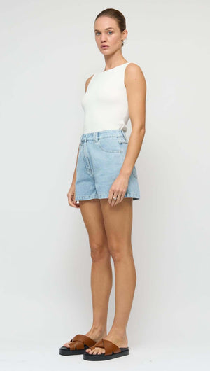 Model wearing a White Reversible Knit Tank Top with blue denim shorts and brown sandals on a neutral background.