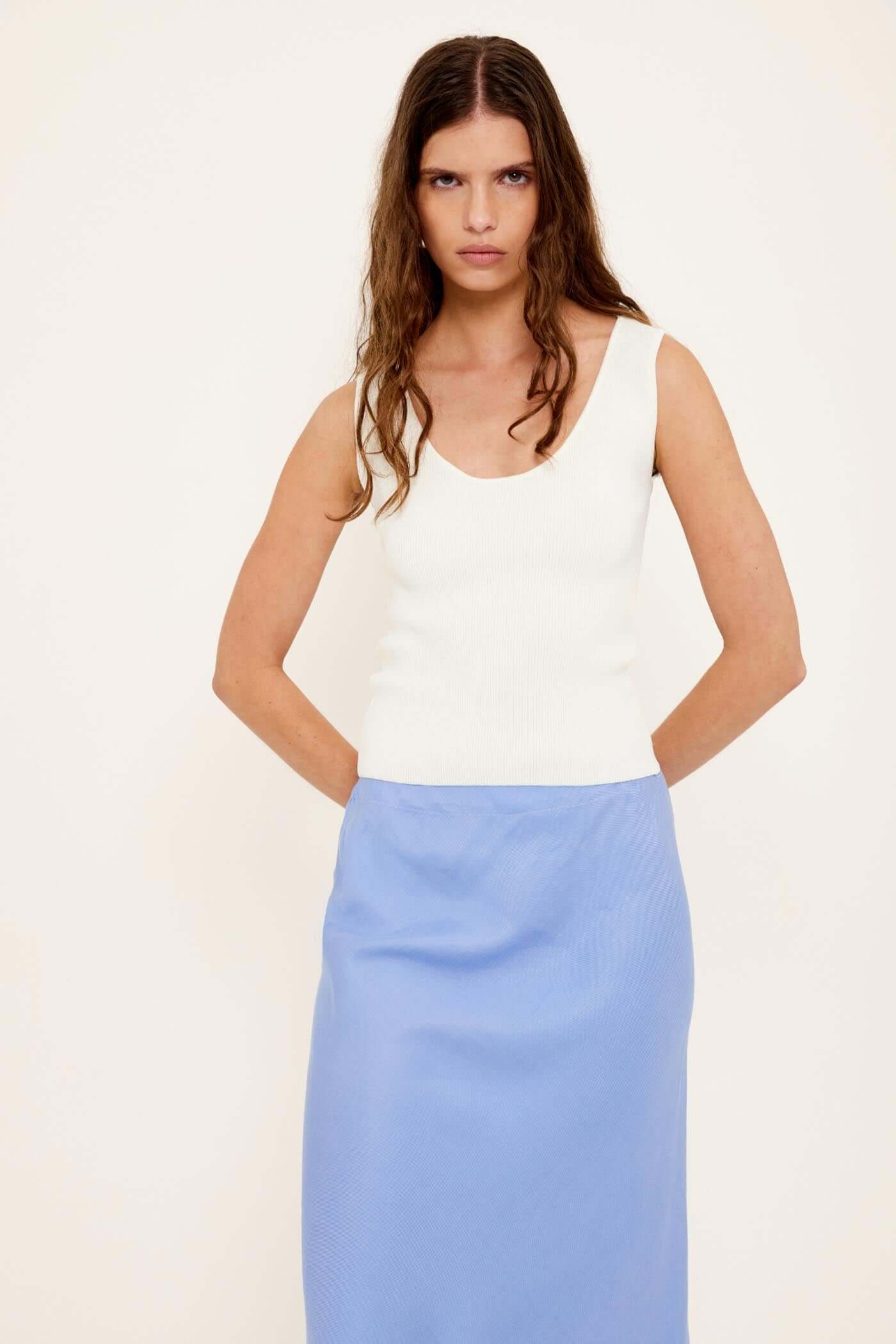 White Reversible Knit Tank Top worn with a blue skirt, showcasing its versatile and modern design.