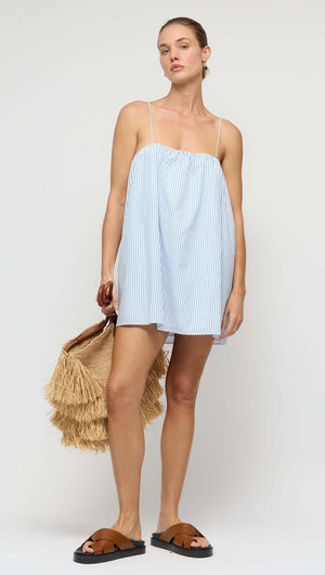 Cotton Blue & White Stripe Mini Dress worn by a model, styled with a straw bag and sandals.