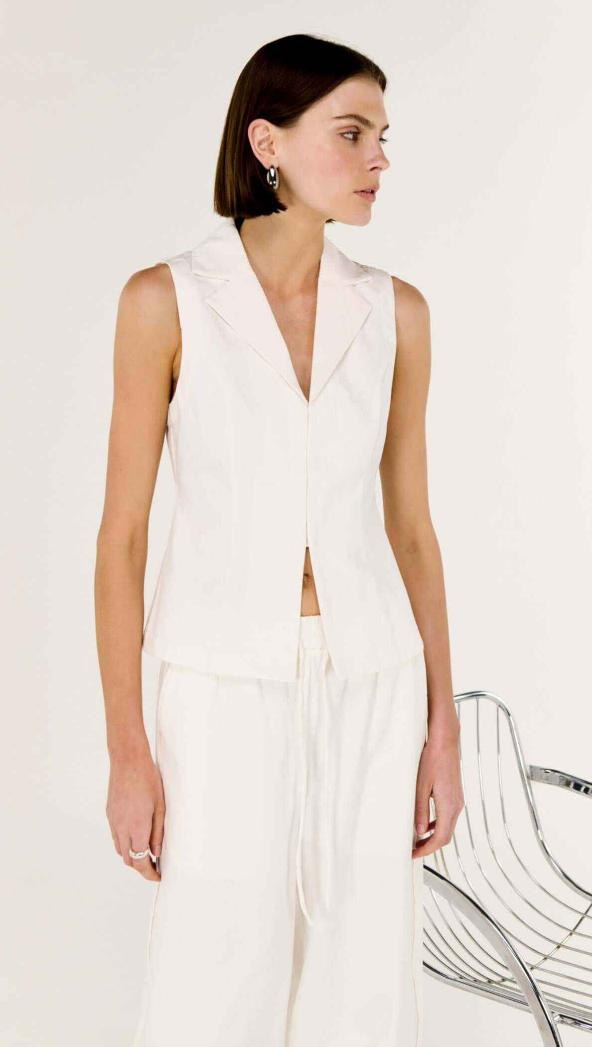 Model wearing a White Cotton Tailored Vest Top featuring a sharp lapel neckline and streamlined fit.