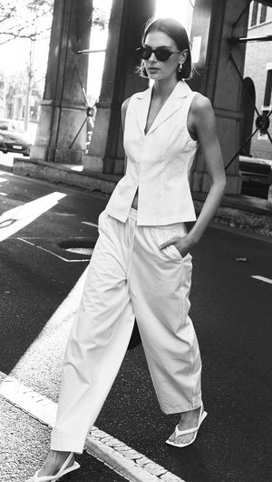White Cotton Tailored Vest Top worn by model walking on city street, paired with wide-leg pants and stylish accessories.