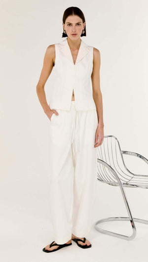 Model wearing a White Cotton Tailored Vest Top paired with white trousers, showcasing a sleek and modern look.