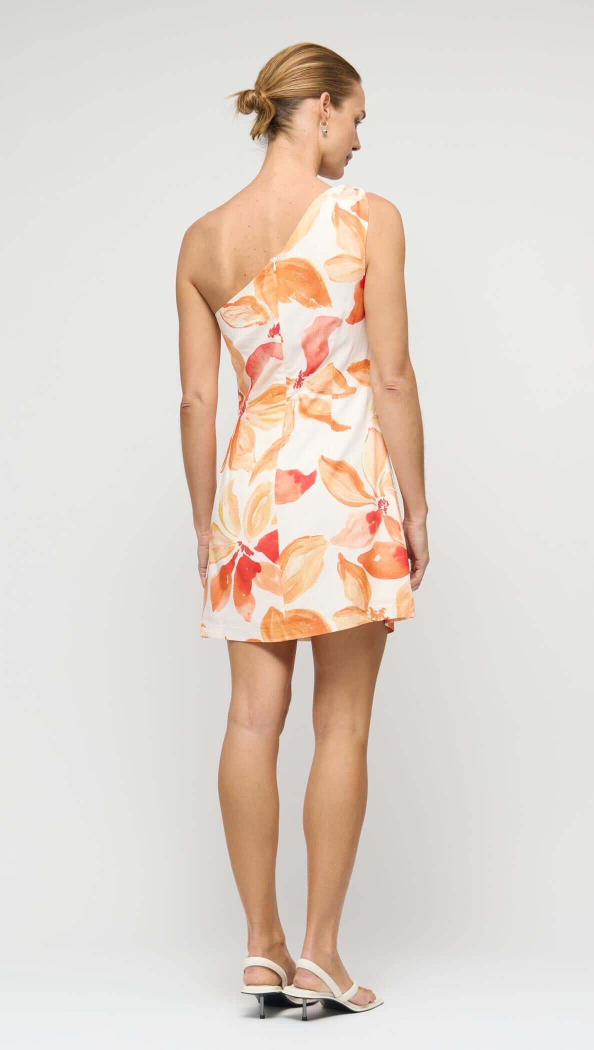 Back view of an Orange & White Floral One Shoulder Mini Dress with a stylish bow-tie shoulder design.