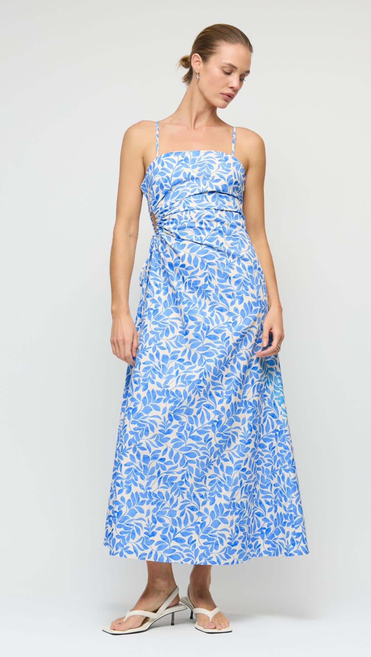 Cotton Blue Leaf Print Cut Out Maxi Dress displayed on a model, featuring a blue and ivory leaf print and flared skirt.