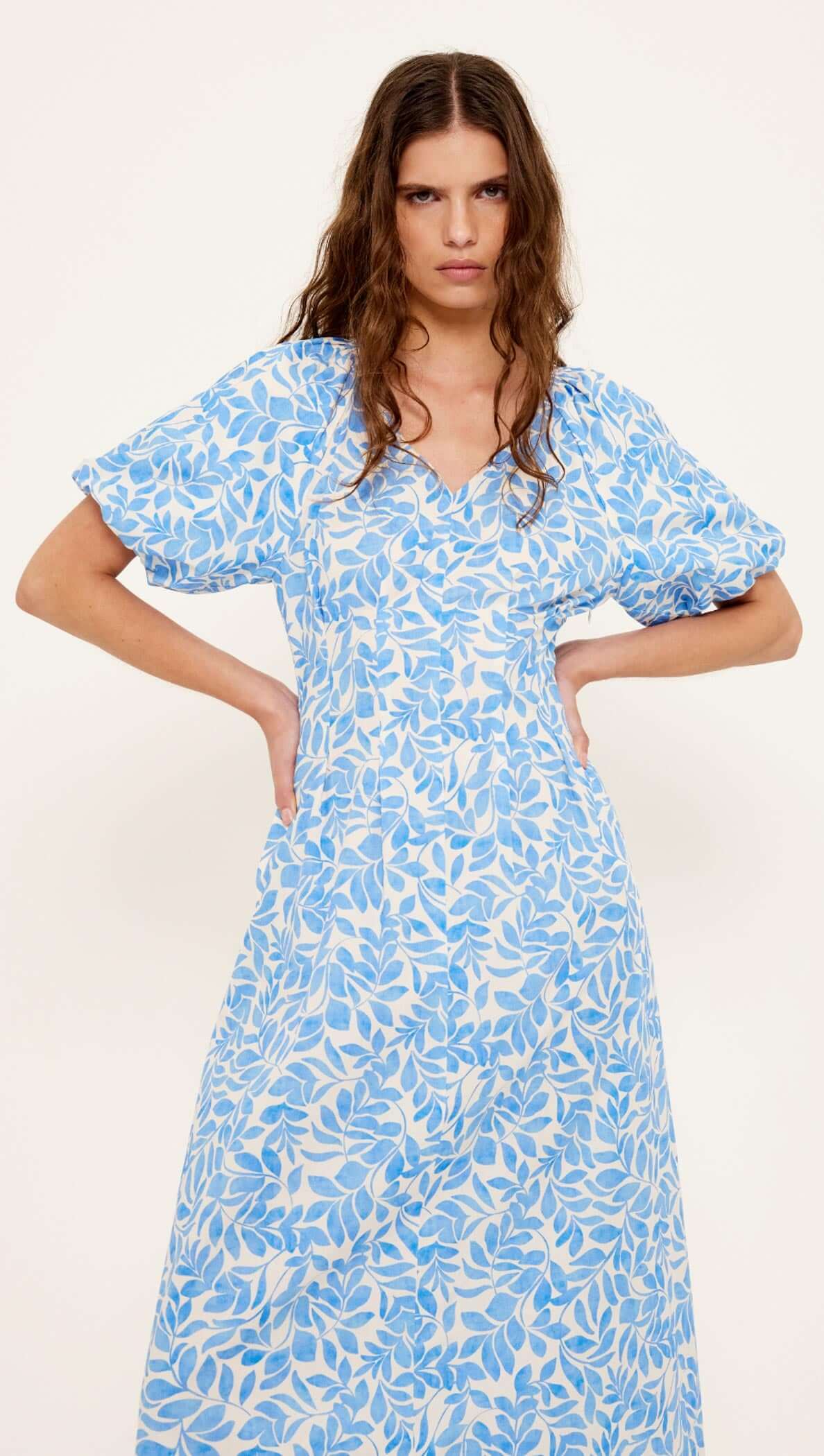 Cotton Blue Leaf Print V-neck Midi Dress worn by a model, featuring short puff sleeves and a flattering silhouette.