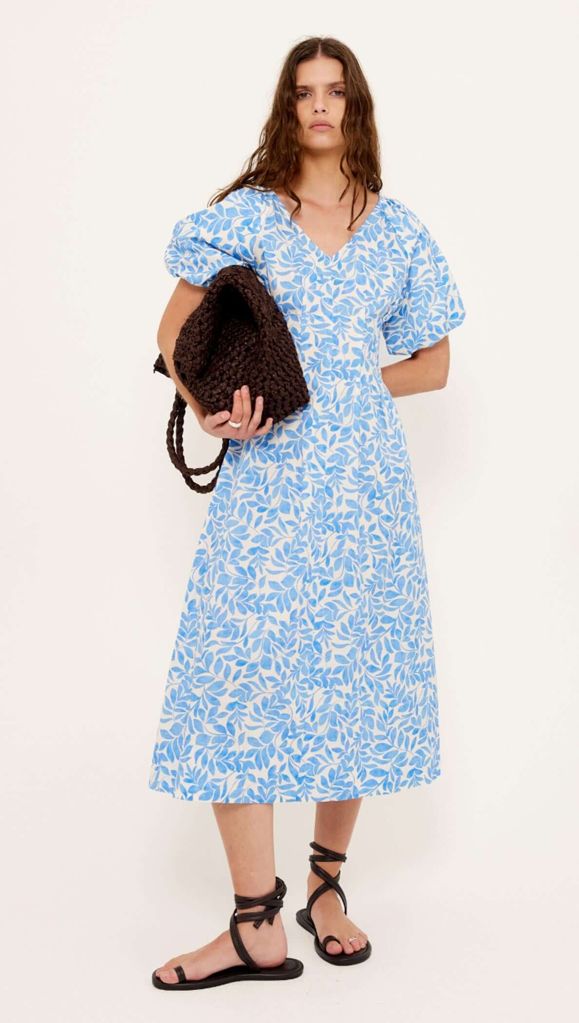 Cotton Blue Leaf Print V-neck Midi Dress worn by a model, featuring short puff sleeves and a flattering silhouette.