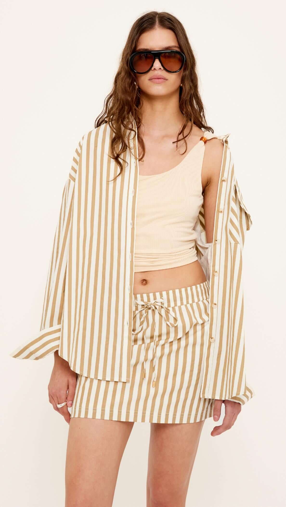 Model wearing the Tan Stretch Tank with Bead Detail styled with a striped shirt and skirt, showcasing summer fashion.