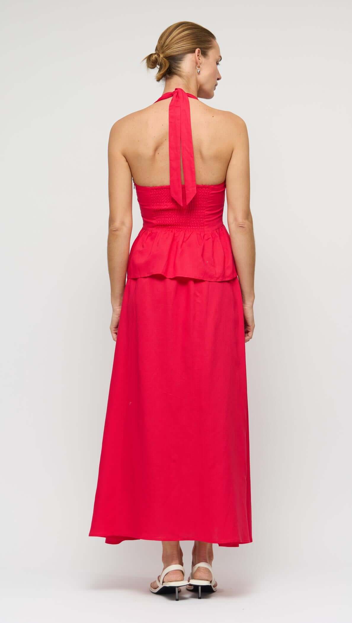 Back view of a woman wearing the Red Linen Blend Maxi Skirt with a peplum detail and halter neck design.