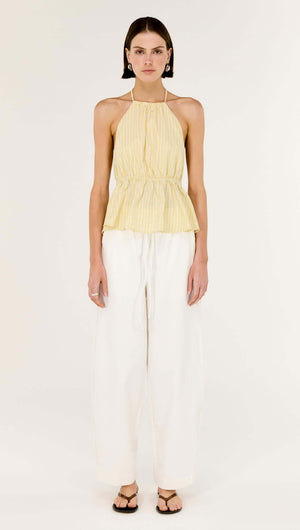 Model wearing a Butter Yellow Low Back Striped Halter Top styled with wide-leg white pants.