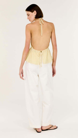 Butter Yellow Low Back Striped Halter Top shown from the back, featuring a halter neckline and open back, paired with white pants.