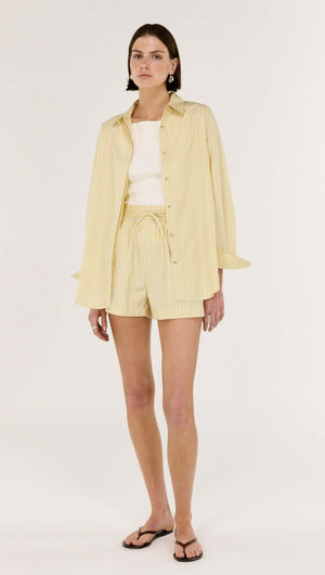 Model wearing a Butter Yellow Striped Shirt paired with shorts, showcasing a relaxed and stylish outfit.