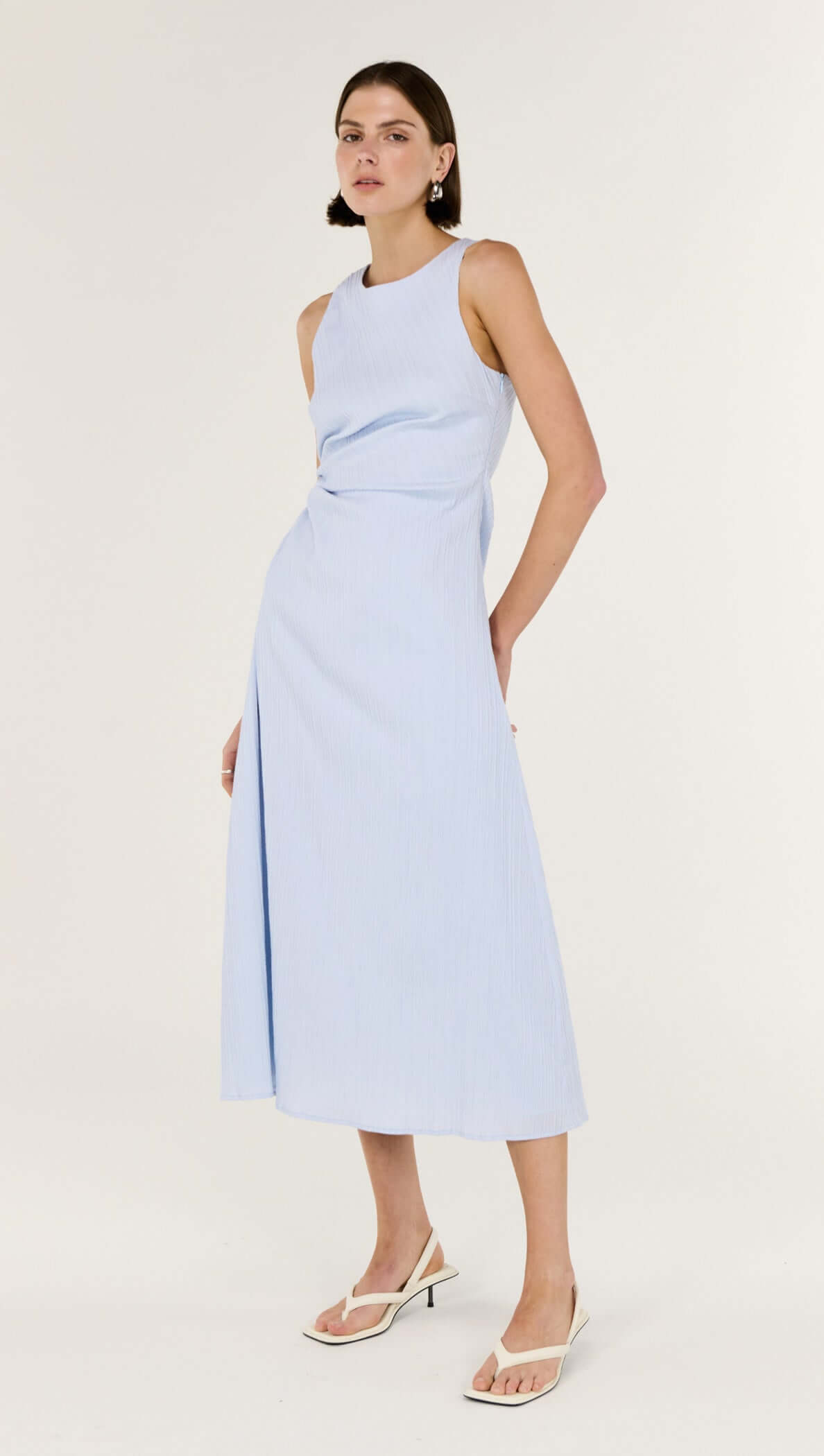 Baby Blue Cotton Textured Cut Out Midi Dress modeled by a woman, featuring a sleeveless design and subtle side cut-out.