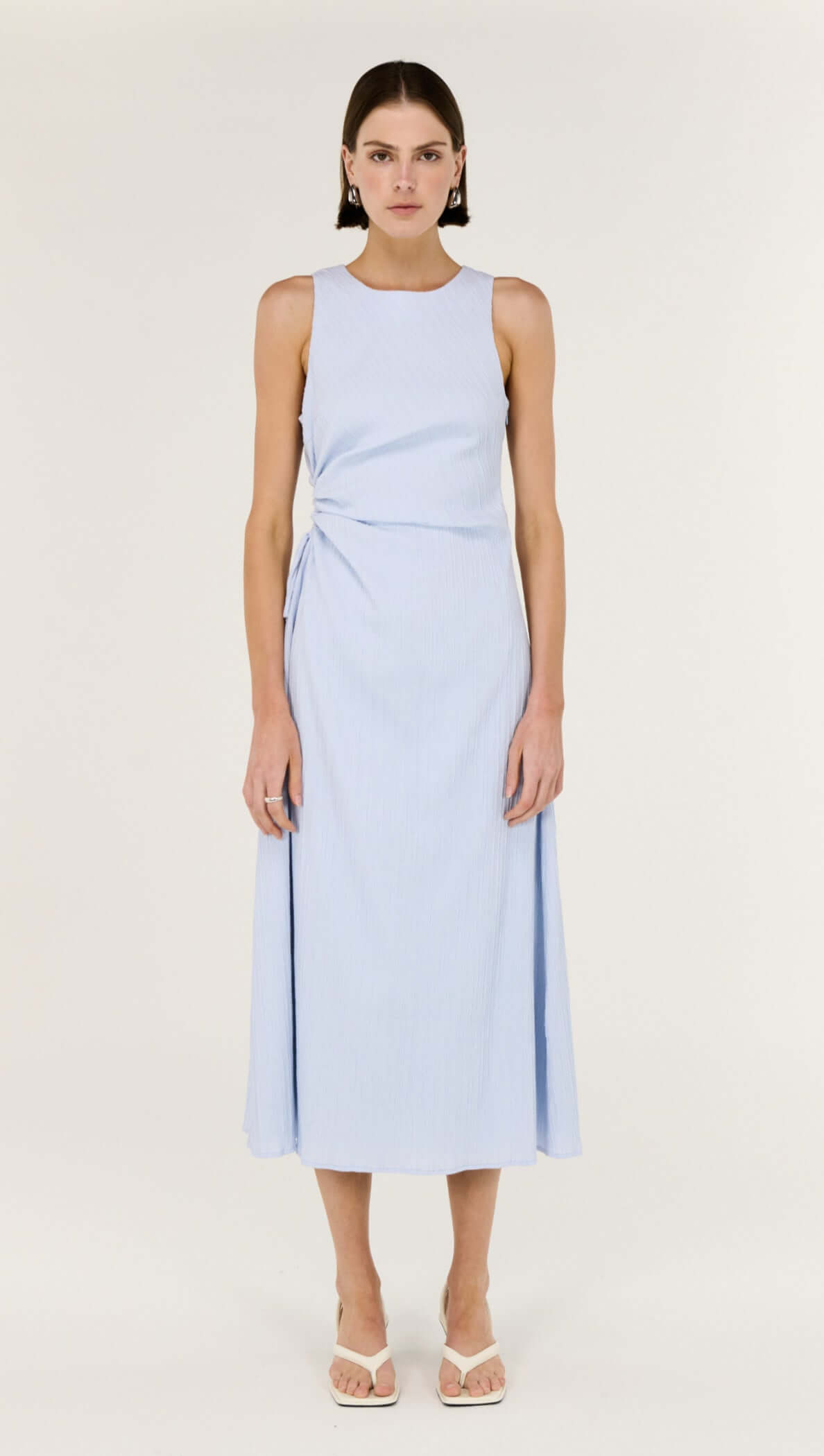 Baby Blue Cotton Textured Cut Out Midi Dress modeled by a woman, featuring a sleeveless design and subtle side cut-out.