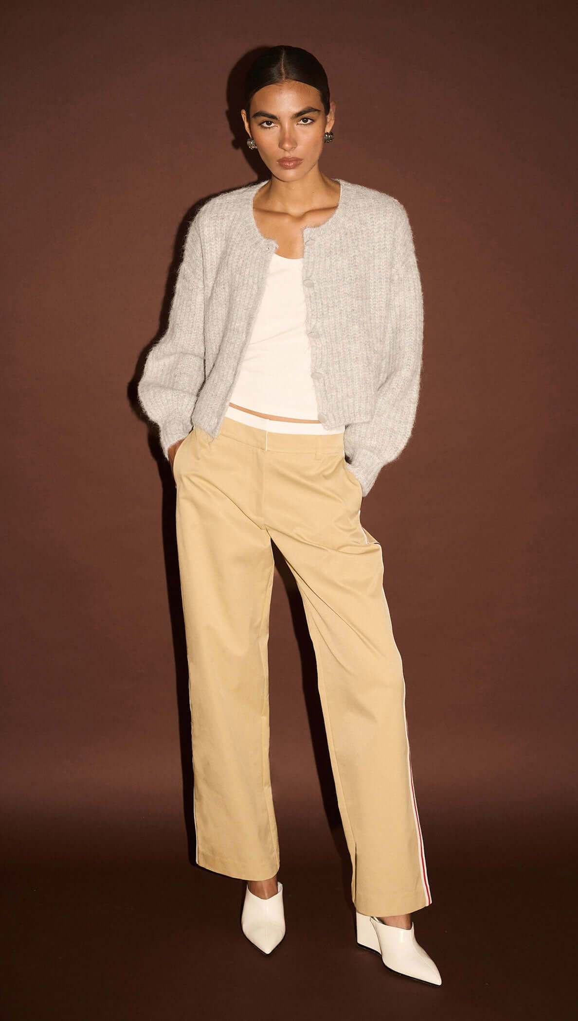 Model wearing Beige Striped Contrast Waist Pants styled with a grey sweater against a brown backdrop.