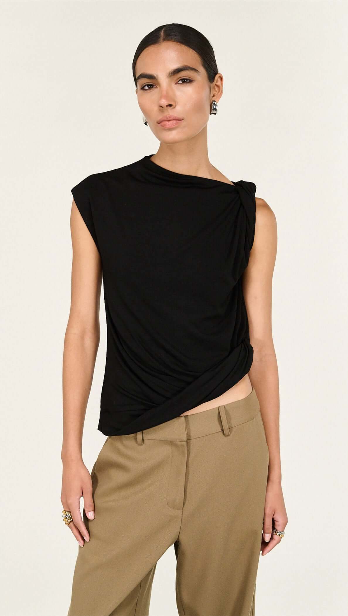 Model wearing a Black Twist Asymmetric Tank, showcasing its elegant twist detail and modern silhouette.