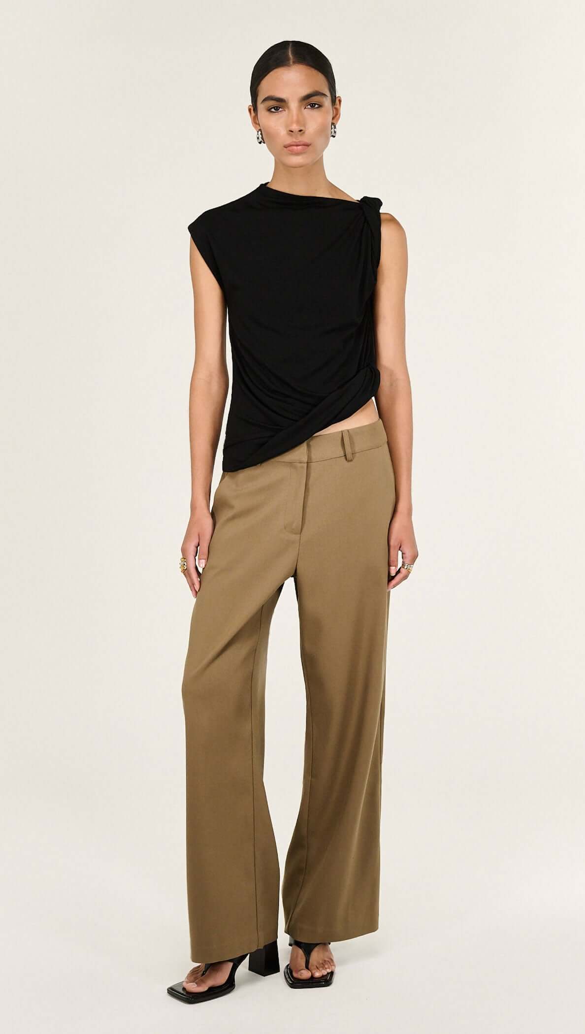 Model wearing a Black Twist Asymmetric Tank, showcasing its elegant twist detail and modern silhouette.