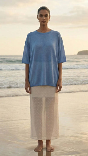 Model at the beach wearing a Blue Round Neck Oversized Knit Tee paired with a sheer skirt.