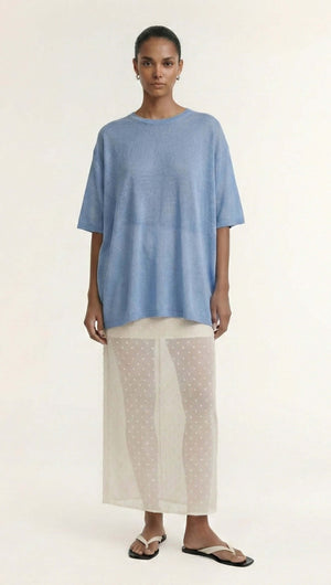 Model wearing a Blue Round Neck Oversized Knit Tee over a sheer skirt, showcasing a relaxed summer outfit.