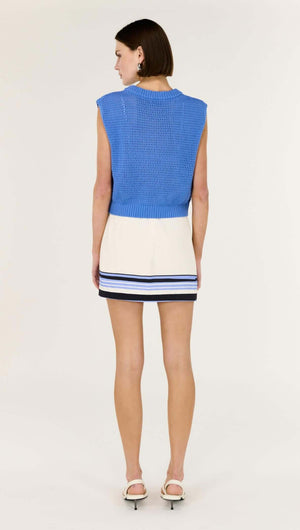 Back view of a model wearing a Blue Wide Gauge Cotton Blend Knit Tank with a white striped skirt.