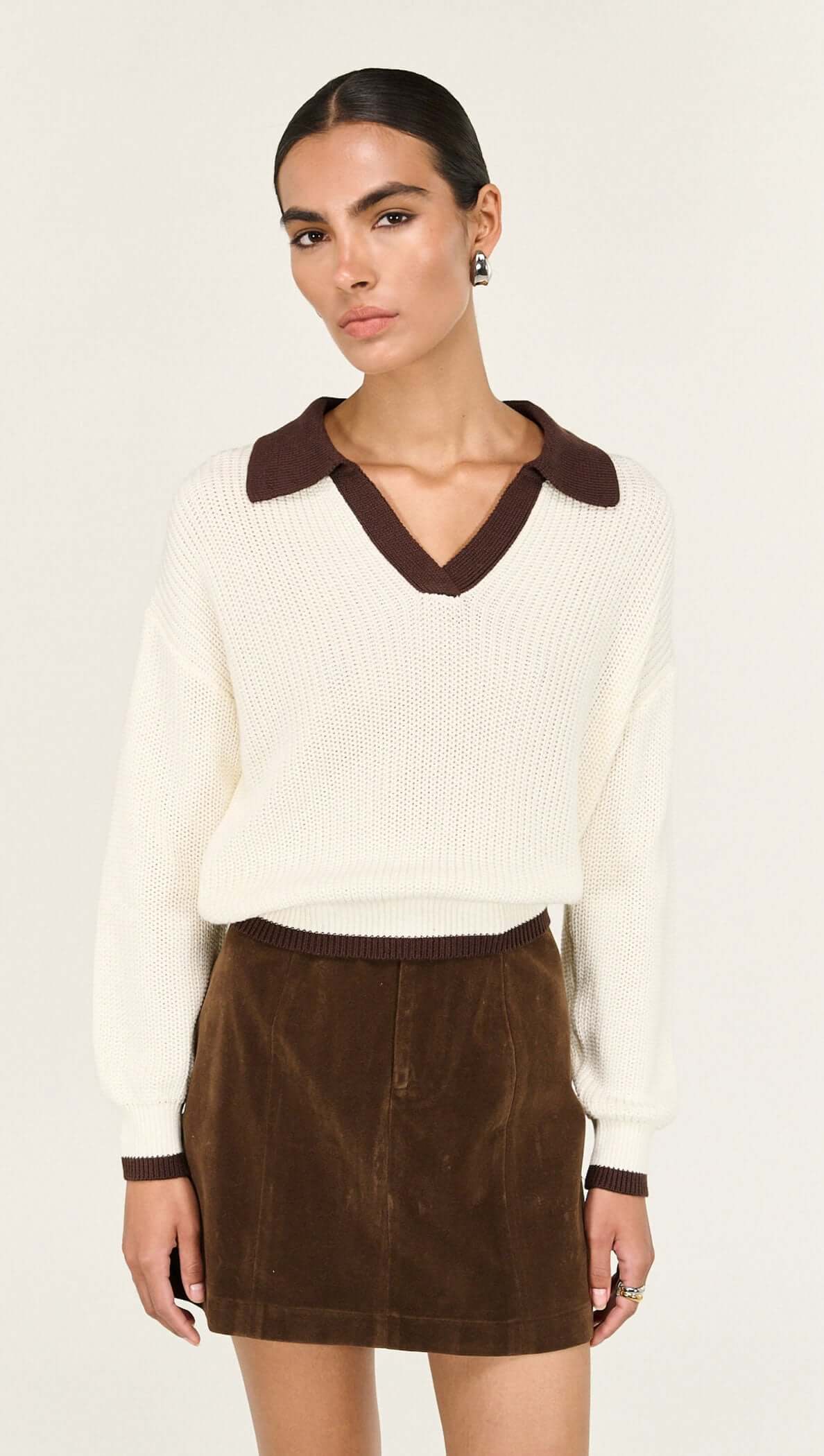 Brown Vegan Suede Mini Skirt styled with a cream sweater and brown collar, showcasing a chic A-line silhouette.