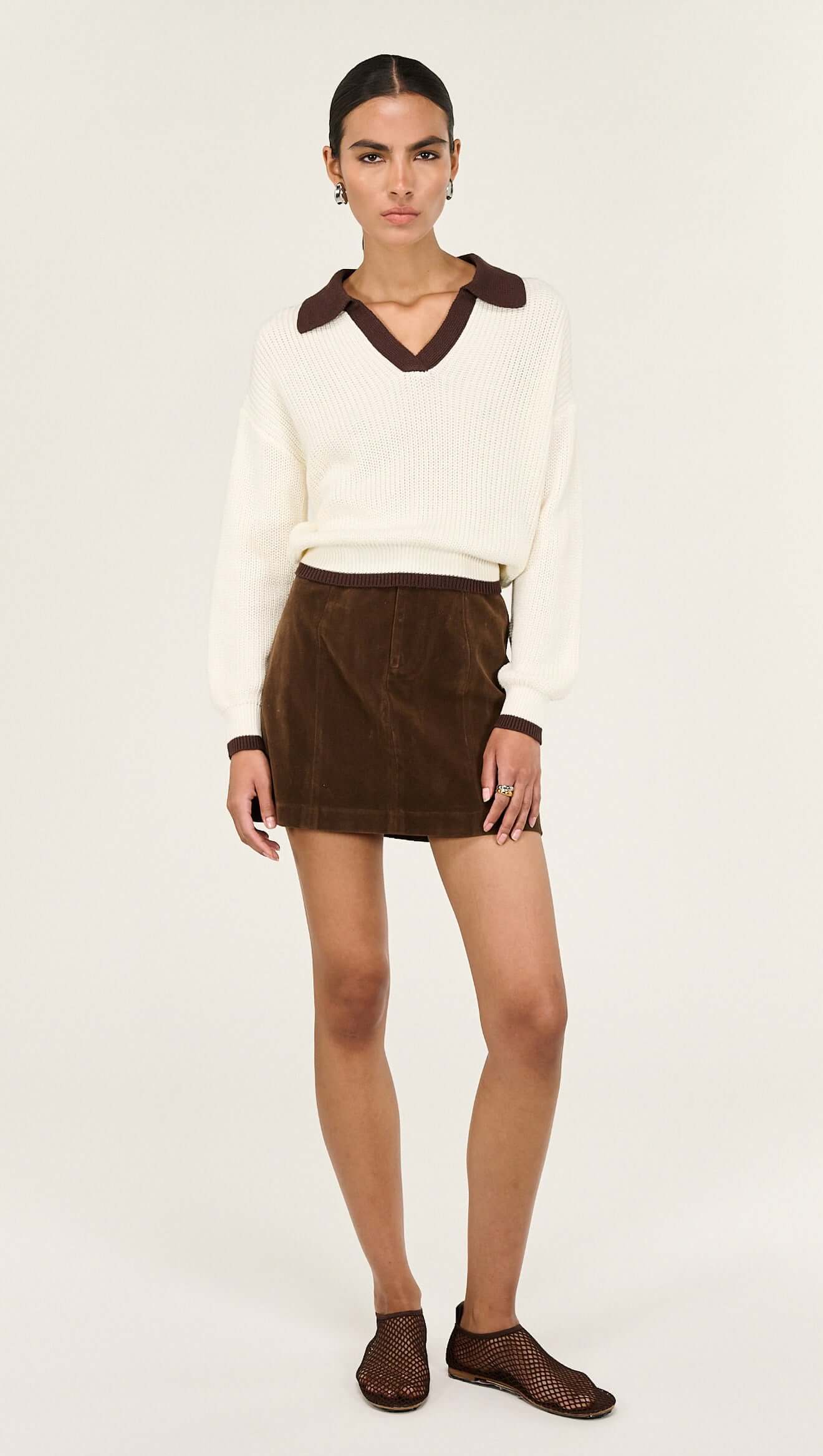 Brown Vegan Suede Mini Skirt styled with a cream sweater and brown collar, showcasing a chic A-line silhouette.