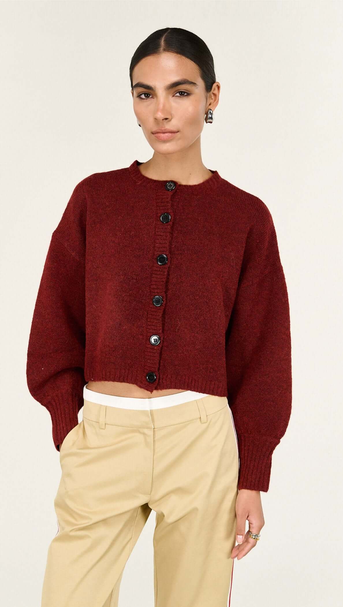 Burgundy Cropped Knit Cardigan styled with high-waisted beige trousers, featuring balloon sleeves and button detailing.