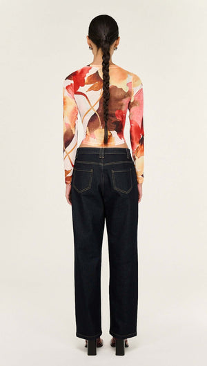 Back view of the model wearing the Burnt Floral Long Sleeve Mesh Top paired with dark denim jeans.