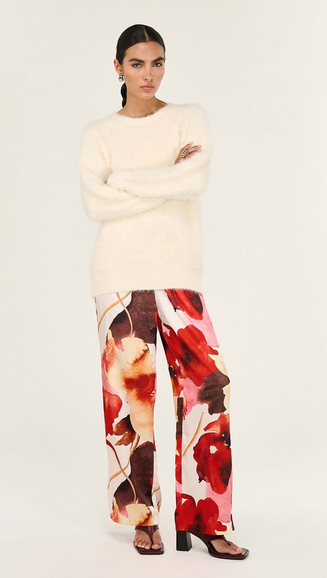 Model wearing Burnt Floral Silky Wide Leg Pants paired with a cream oversized sweater, showcasing floral design and relaxed fit.