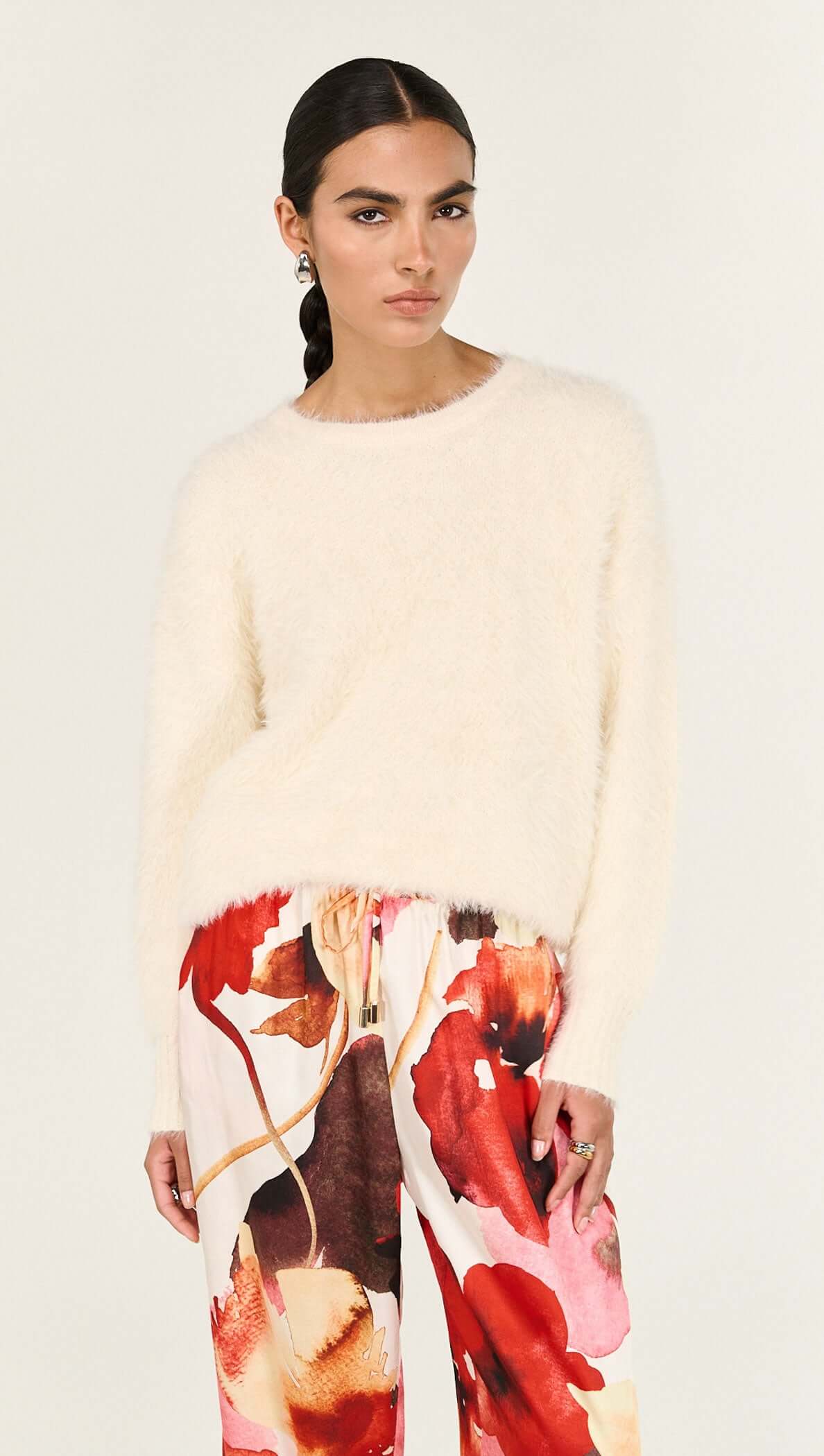 Model wearing Burnt Floral Silky Wide Leg Pants paired with a cream oversized sweater, showcasing floral design and relaxed fit.