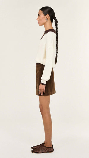 Side view of a model wearing a Chocolate Contrast Polo Knit Jumper paired with a brown skirt.